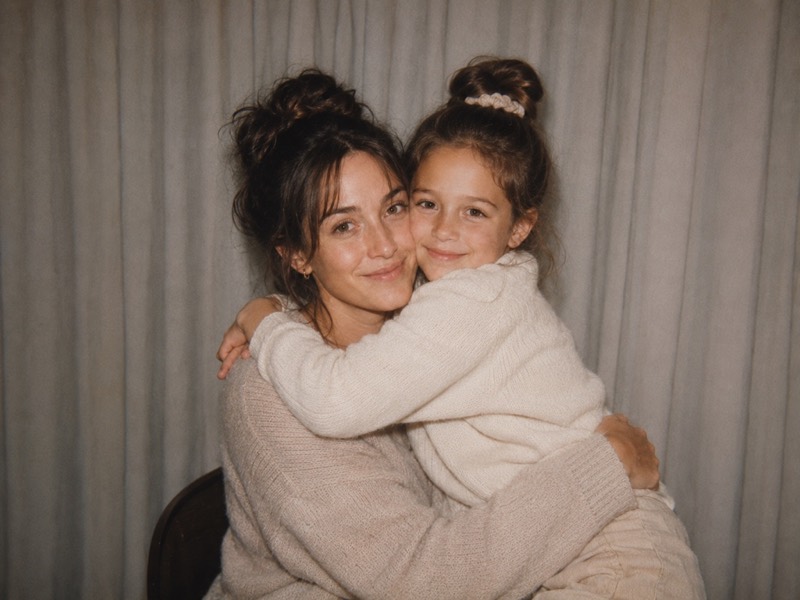 An adult and a child cheek to cheek.
